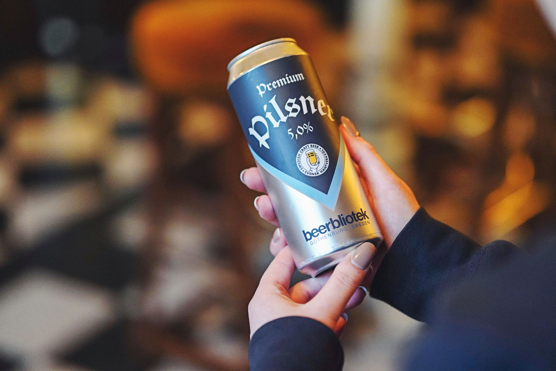 A photo of Madison Simpson holding a can of Premium Pilsner, a Pilsner, brewed by Swedish Craft Beer brewery, Beerbliotek, in Gothenburg. Premium Pilsner is Beerbliotek's first 500ml Can.